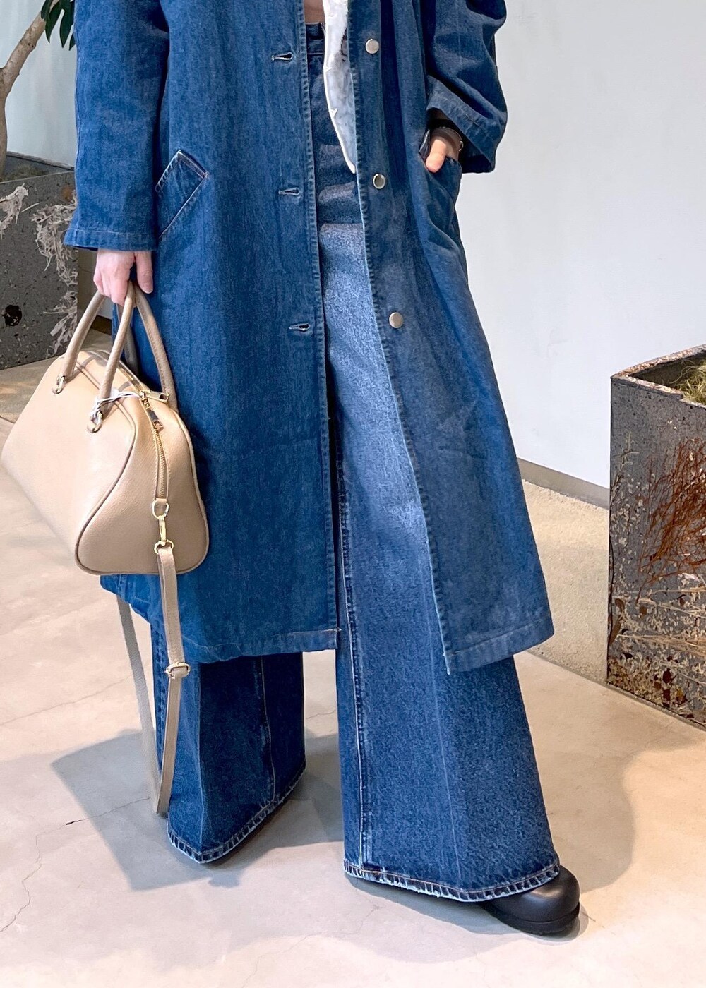 ベージュ系のボストンバッグ、ブルー系のデニムパンツ、ホワイト系のベストを着用したレディースの冬コーディネートの6枚目の写真