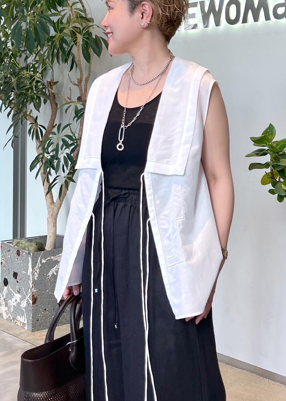 ブラック系のその他パンツ、ブラウン系のトートバッグ、ホワイト系のシャツ/ブラウスを着用したレディースの夏コーディネートの6枚目の写真