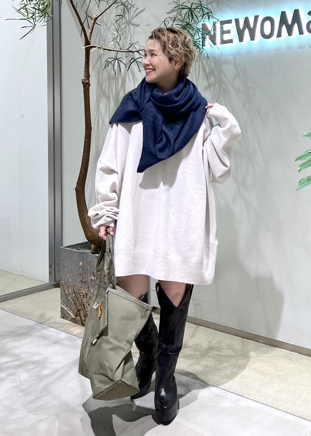 ブラック系のブーツ、グリーン系のトートバッグを着用したレディースの秋コーディネートの3枚目の写真