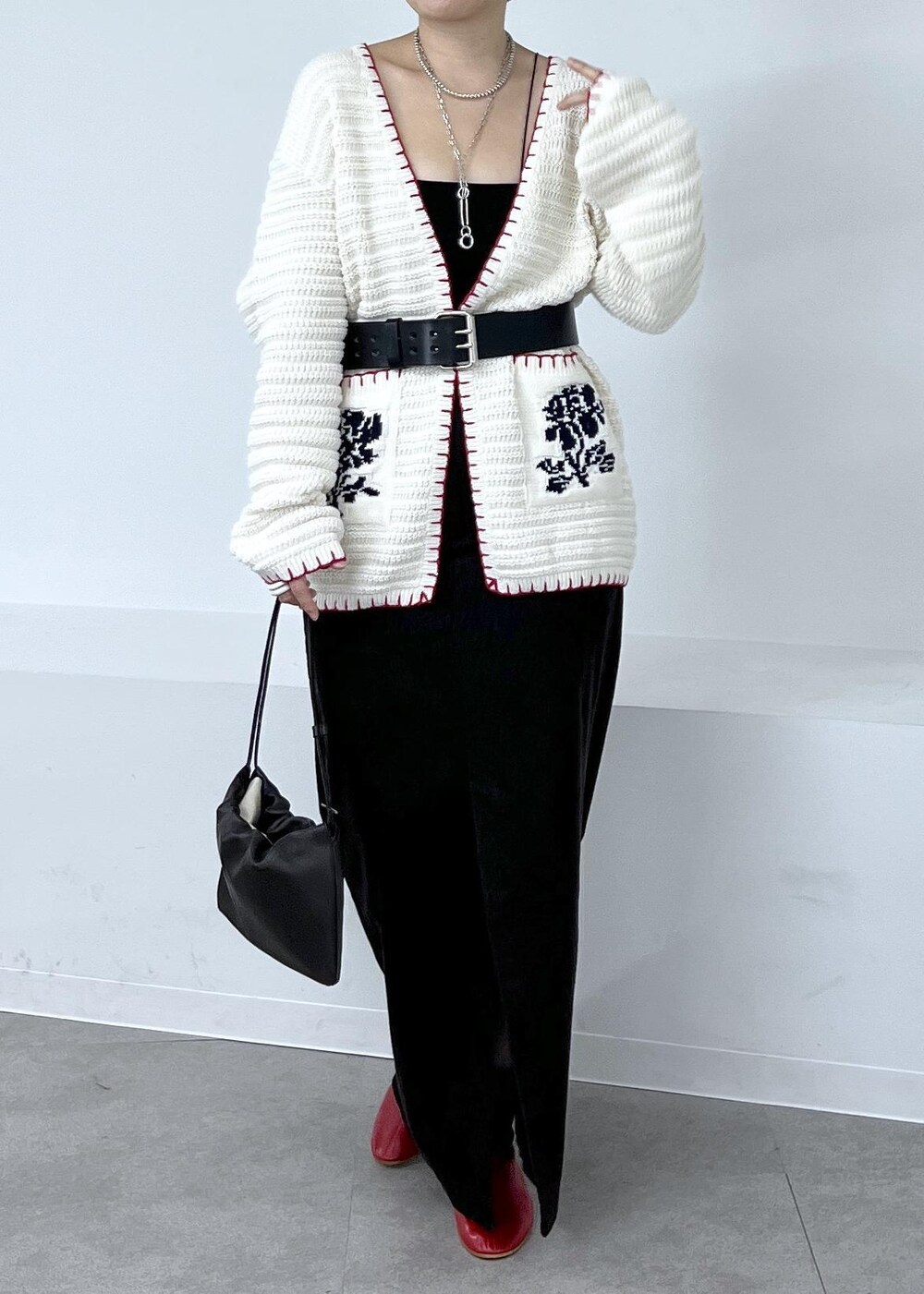 グレー系のスカート、ホワイト系のニット/セーター、レッド系のブーツを着用したレディースの秋コーディネートの5枚目の写真