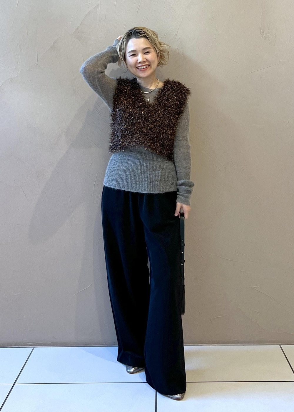 ブラック系のステンカラーコート、グレー系のニット/セーター、ブラック系のその他パンツを着用したレディースの冬コーディネートの2枚目の写真