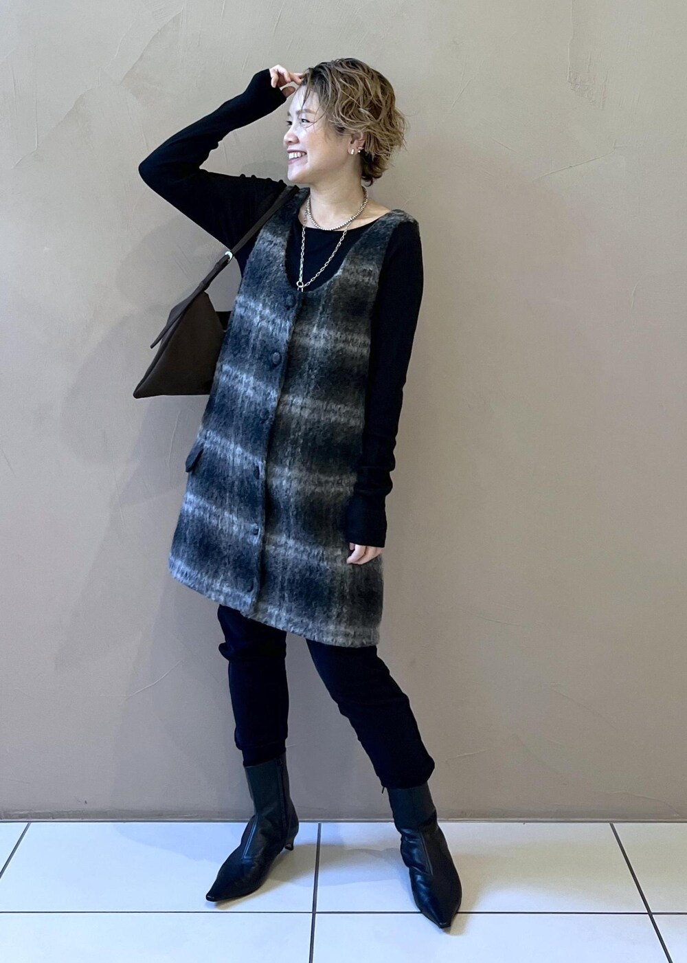 グレー系のジャンパースカート、ブラウン系のショルダーバッグ、ブラック系のTシャツ/カットソーを着用したレディースの秋コーディネートの4枚目の写真