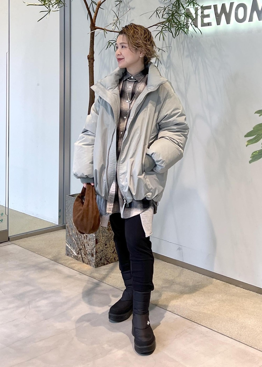 グリーン系のダウンジャケット/コート、ブラウン系のハンドバッグ、ブラック系のブーツを着用したレディースの秋コーディネートの3枚目の写真