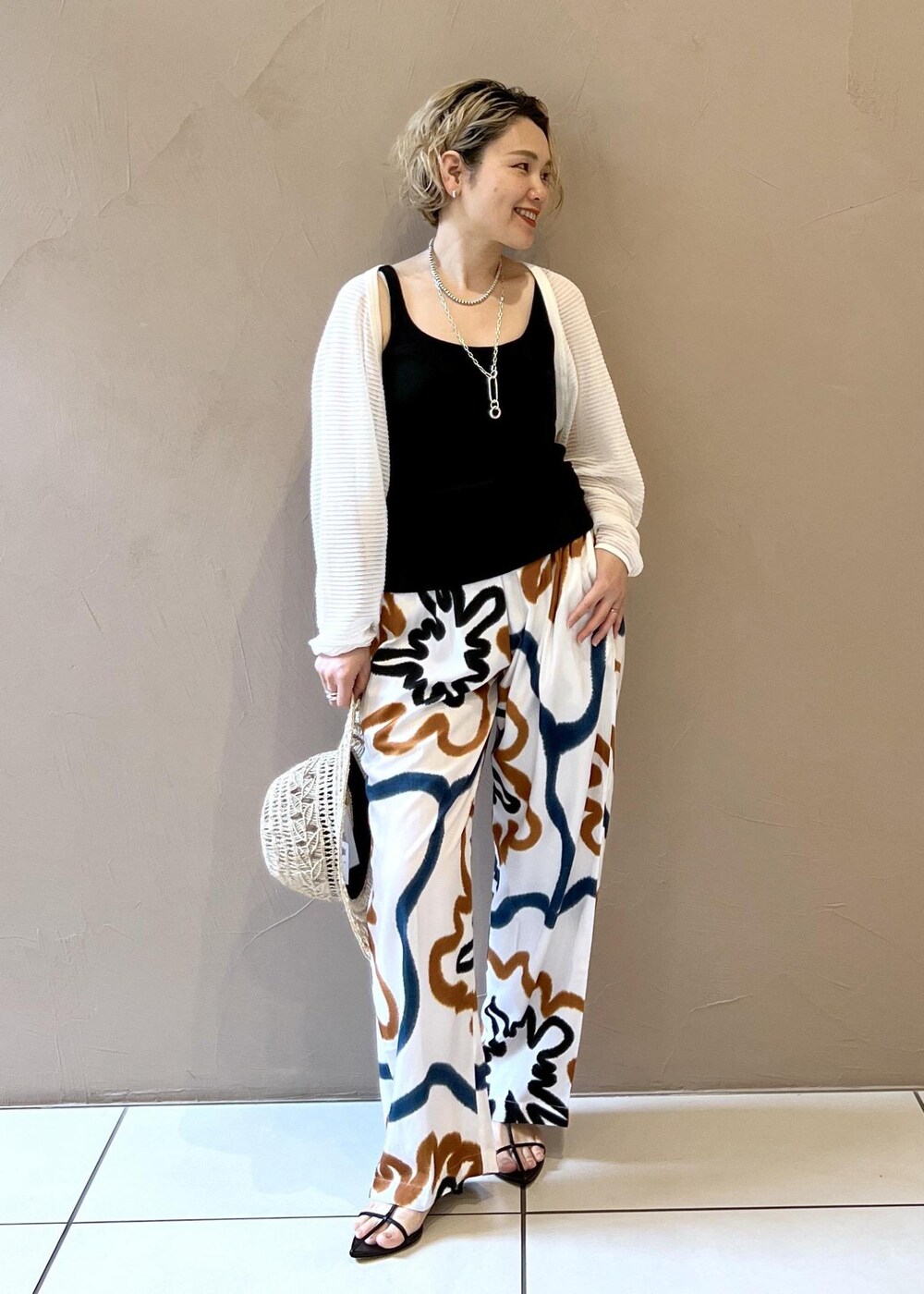 ブラック系のサンダル、ブラック系のタンクトップ、ホワイト系のカーディガン/ボレロを着用したレディースの春コーディネートの3枚目の写真