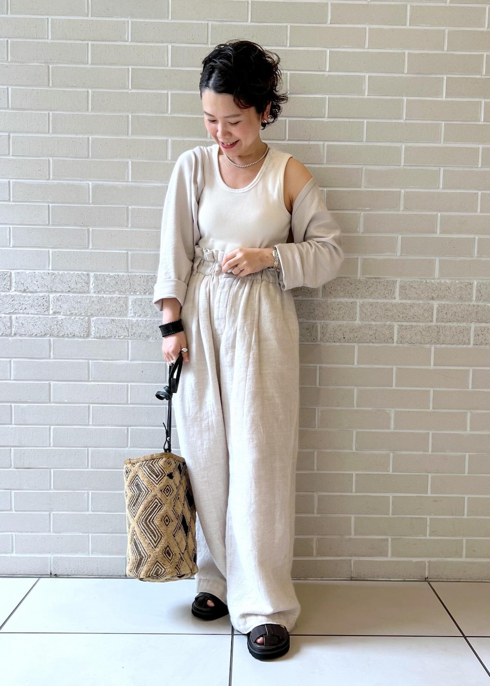 ブラウン系のサンダル、ホワイト系のカーディガン/ボレロ、ホワイト系のスラックスを着用したレディースの夏コーディネートの4枚目の写真