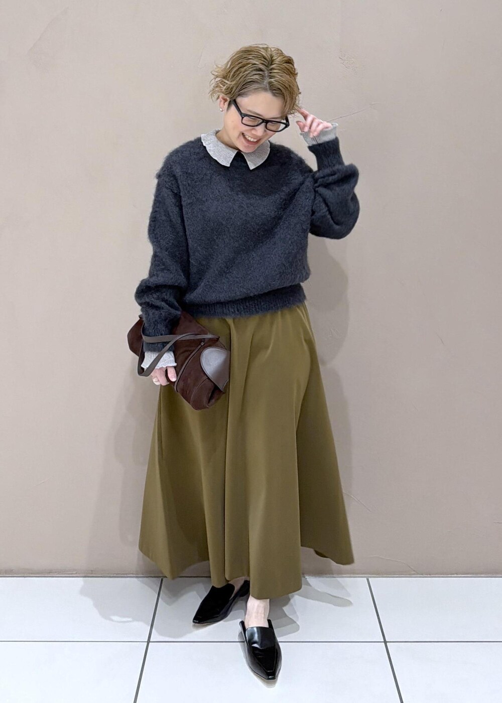 ブラウン系のスカート、ブラック系のローファー、グレー系のニット/セーターを着用したレディースの冬コーディネートの3枚目の写真