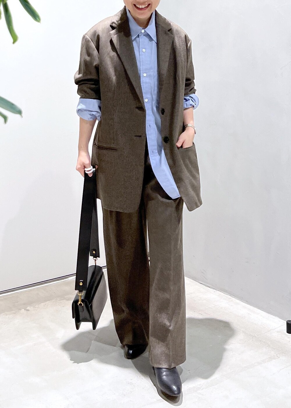 ブルー系のシャツ/ブラウス、ブラック系のショルダーバッグ、ブラウン系のスラックスを着用したレディースの秋コーディネートの5枚目の写真