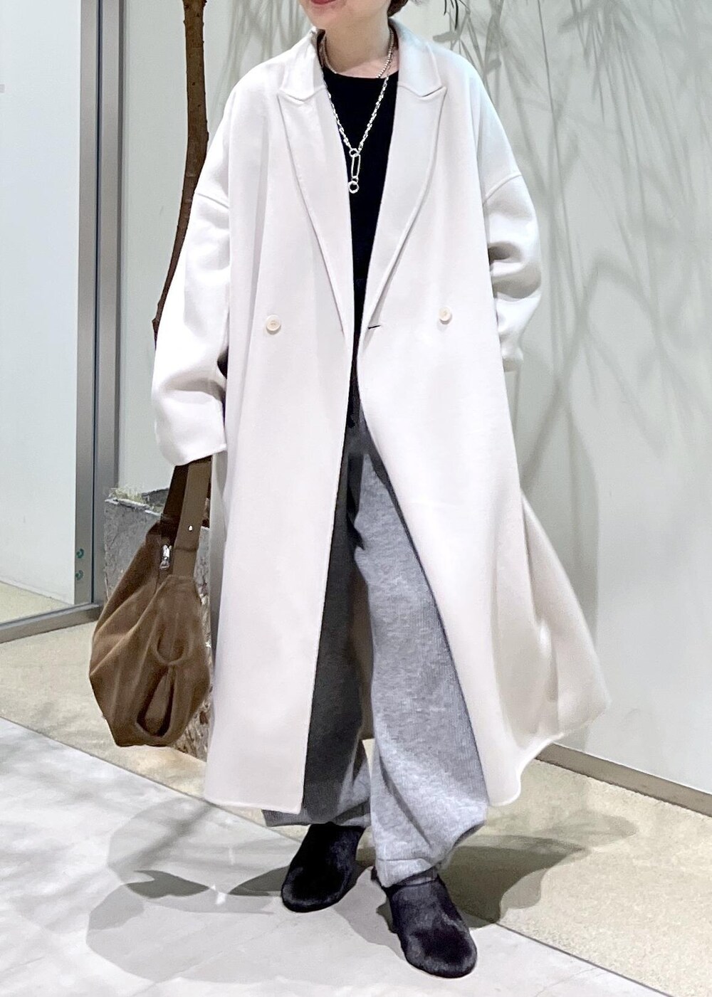 ホワイト系のチェスターコート、ブラック系のスウェット、ブラウン系のショルダーバッグを着用したレディースの秋コーディネートの4枚目の写真