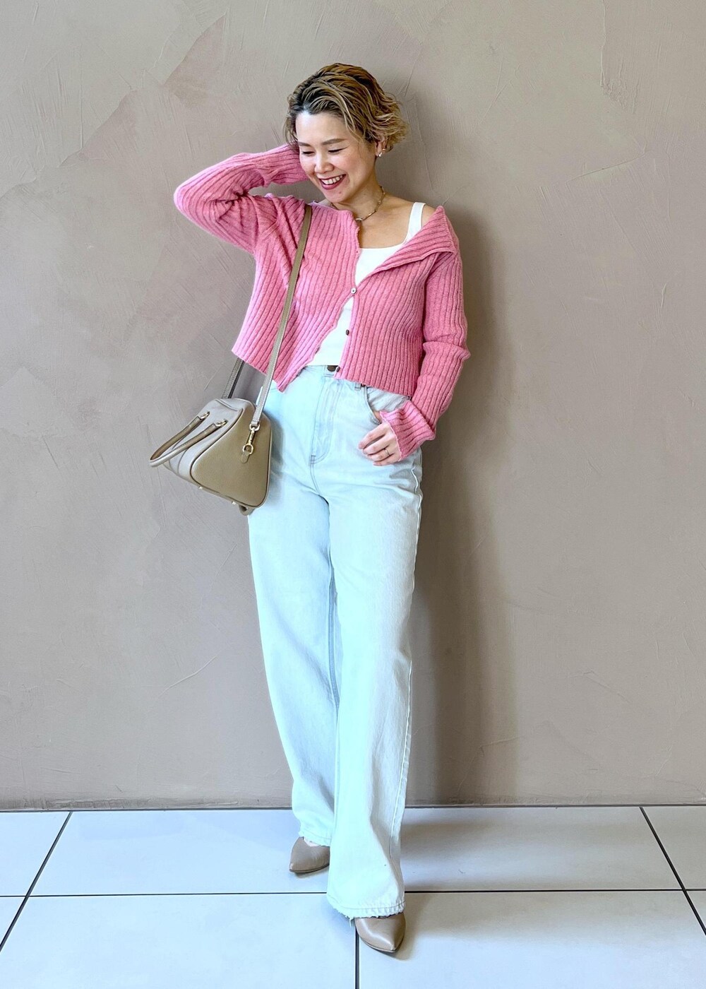 ベージュ系のボストンバッグ、ベージュ系のステンカラーコート、ブルー系のデニムパンツを着用したレディースの冬コーディネートの9枚目の写真