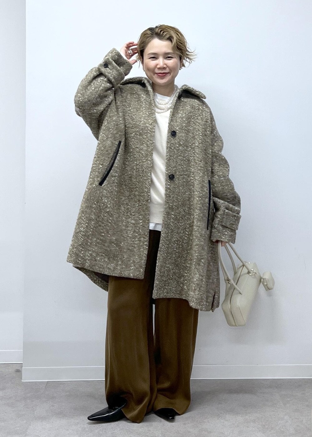 ホワイト系のスウェット、ベージュ系のステンカラーコート、ブラウン系のその他パンツを着用したレディースの秋コーディネートの9枚目の写真