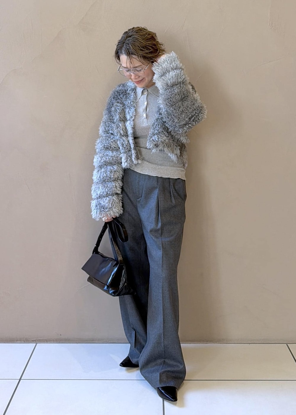 ブラック系のショルダーバッグ、グレー系のスラックス、グレー系のカーディガン/ボレロを着用したレディースの冬コーディネートの2枚目の写真