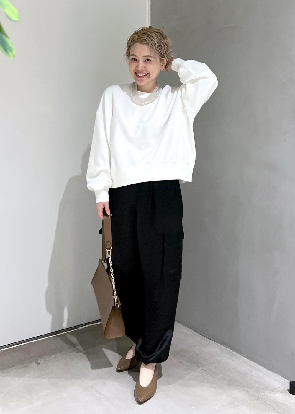 ブラウン系のショルダーバッグ、ブラック系のカーゴパンツ、ホワイト系のスウェットを着用したレディースの秋コーディネートの9枚目の写真