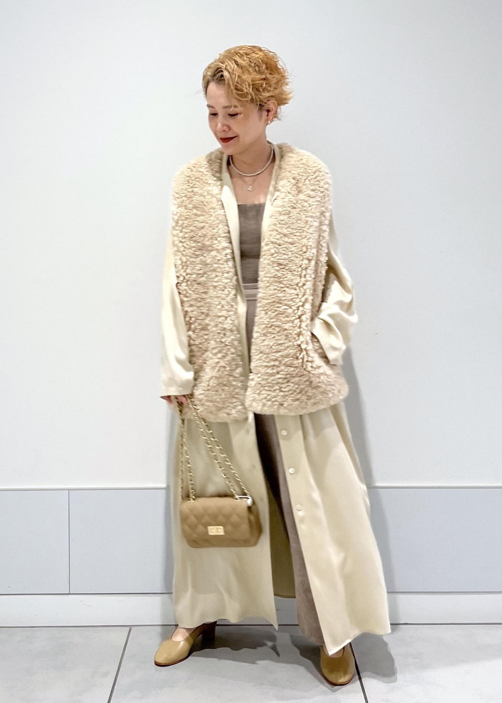 グレー系のカーゴパンツ、ベージュ系のベスト、グレー系のキャミソールを着用したレディースの秋コーディネートの3枚目の写真