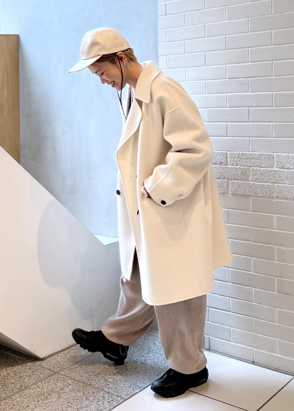 ホワイト系のピーコート、グレー系のカーゴパンツ、ブラウン系のニット/セーターを着用したレディースの秋コーディネートの3枚目の写真