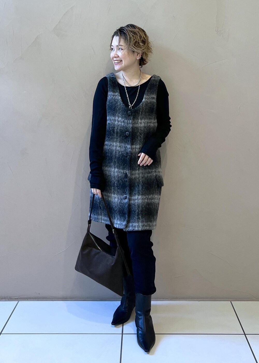 グレー系のジャンパースカート、ブラウン系のショルダーバッグ、ブラック系のTシャツ/カットソーを着用したレディースの秋コーディネートの3枚目の写真