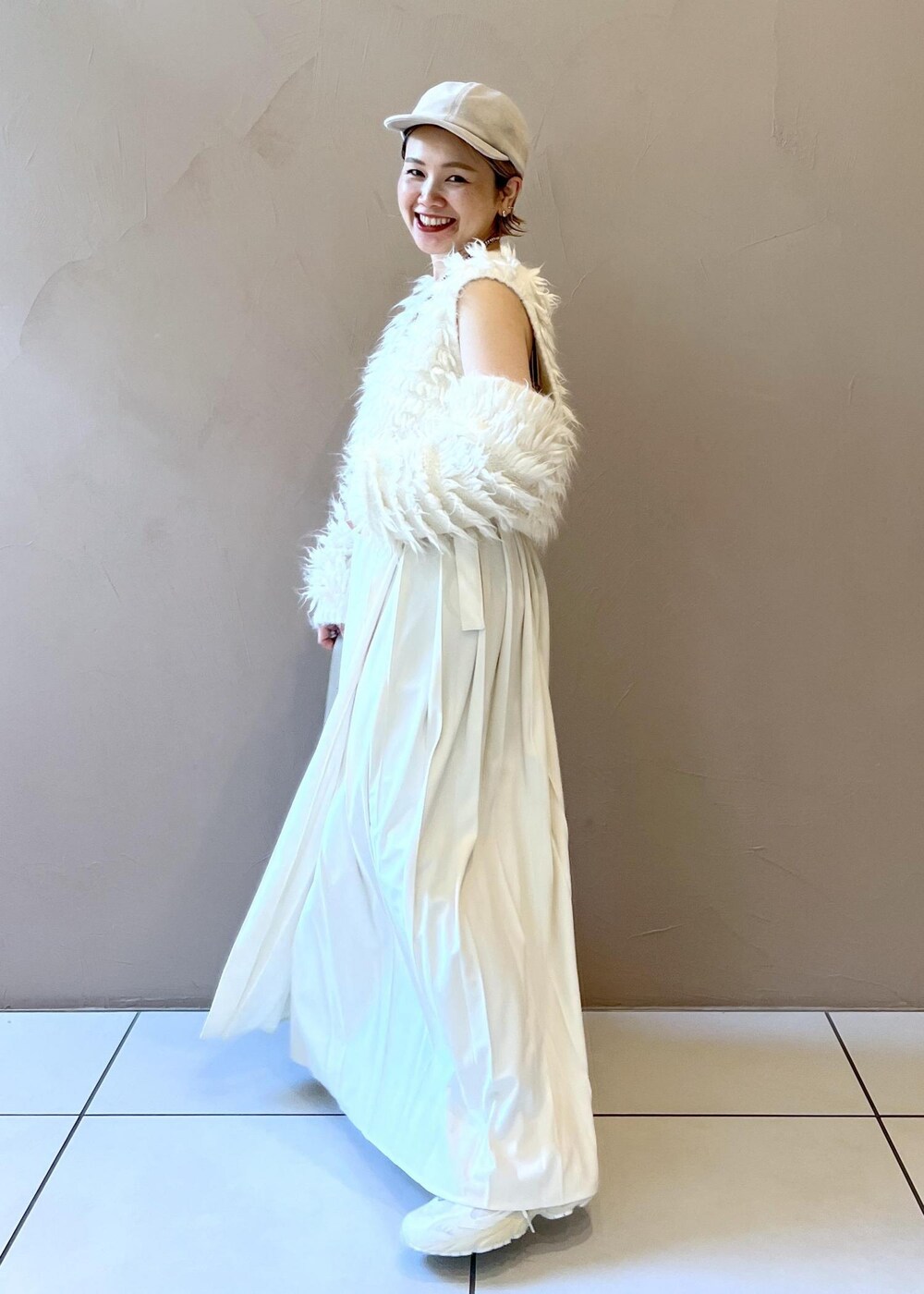 グレー系のショルダーバッグ、ホワイト系のベスト、ホワイト系のキャップを着用したレディースの秋コーディネートの4枚目の写真