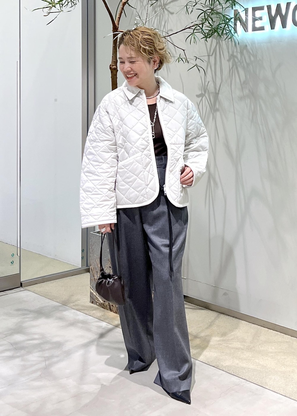 ピンク系のブルゾン、ブラウン系のハンドバッグ、ブラック系のパンプスを着用したレディースの秋コーディネートの2枚目の写真