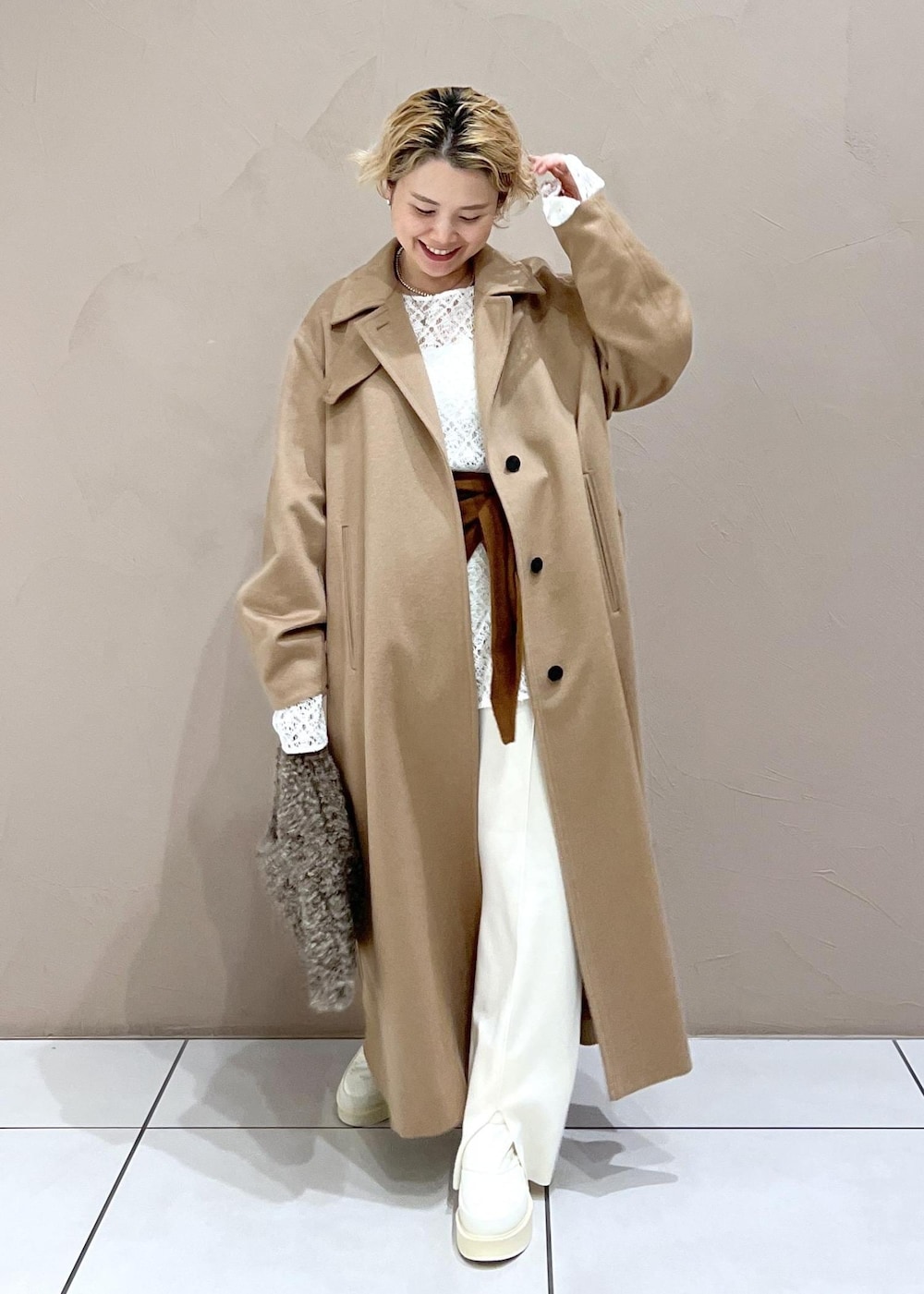 ブラウン系のハンドバッグ、ホワイト系のTシャツ/カットソー、イエロー系のステンカラーコートを着用したレディースの冬コーディネートの6枚目の写真