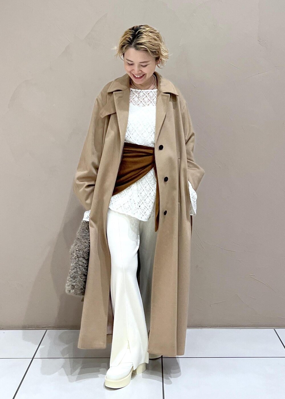 ブラウン系のハンドバッグ、ホワイト系のTシャツ/カットソー、イエロー系のステンカラーコートを着用したレディースの冬コーディネートの8枚目の写真