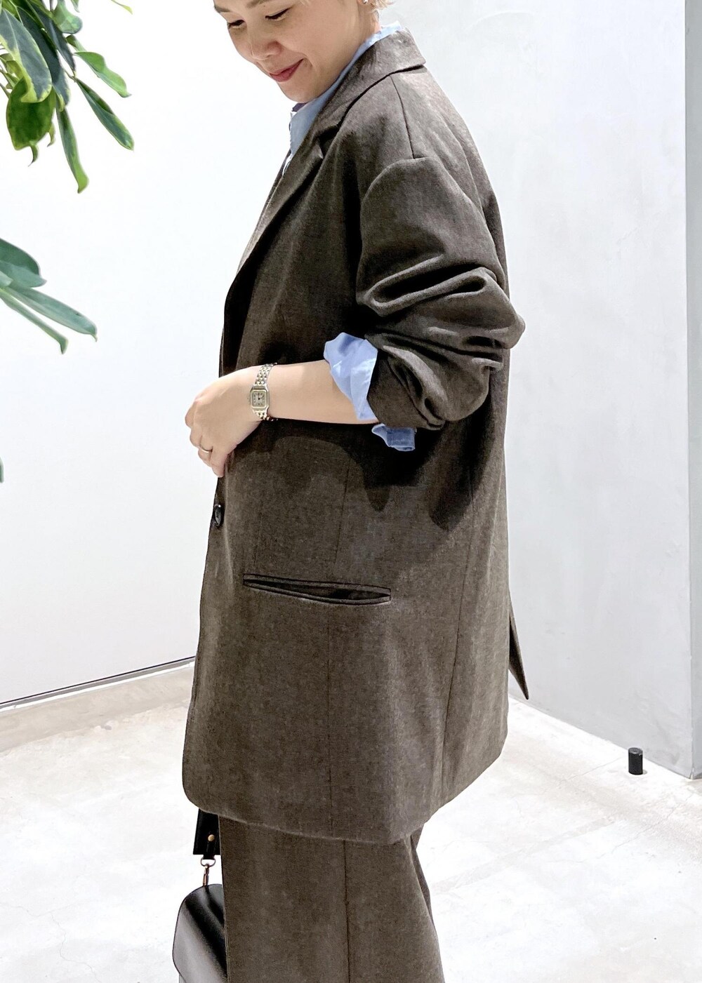 ブルー系のシャツ/ブラウス、ブラック系のショルダーバッグ、ブラウン系のスラックスを着用したレディースの秋コーディネートの8枚目の写真