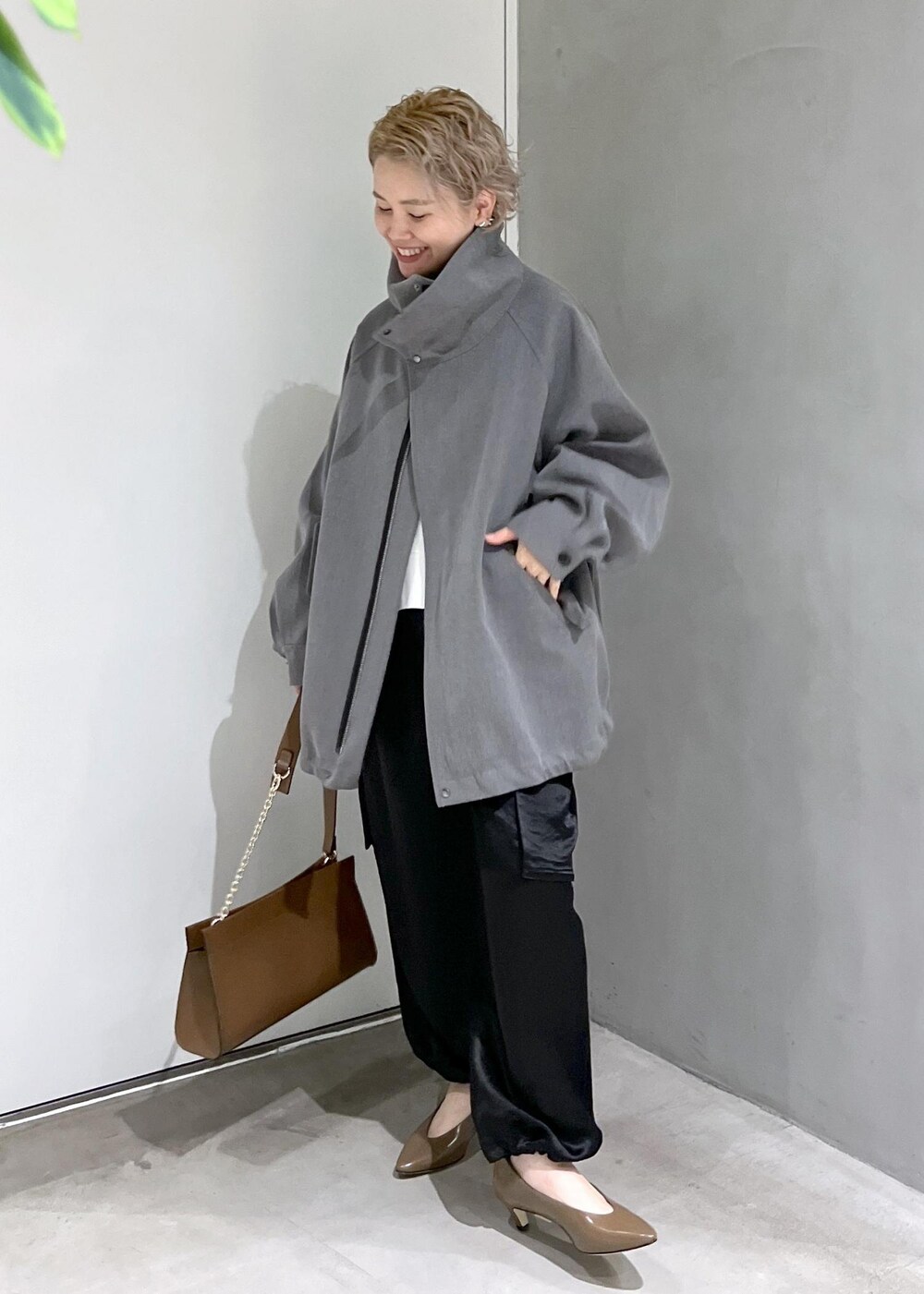 ブラウン系のショルダーバッグ、ブラック系のカーゴパンツ、ホワイト系のスウェットを着用したレディースの秋コーディネートの2枚目の写真