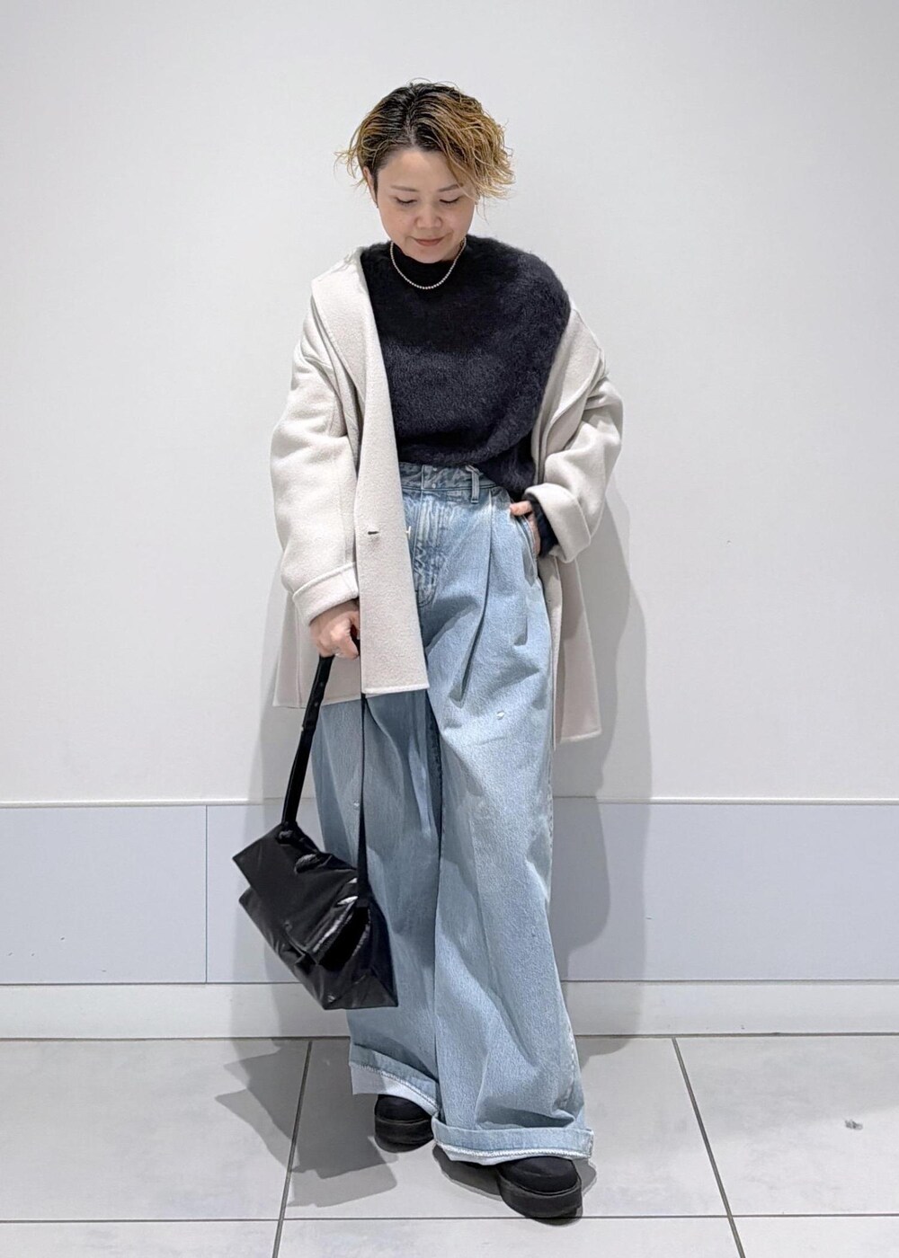 ブラック系のショルダーバッグ、ホワイト系のその他アウター、ブラック系のブーツを着用したレディースの秋コーディネートの4枚目の写真