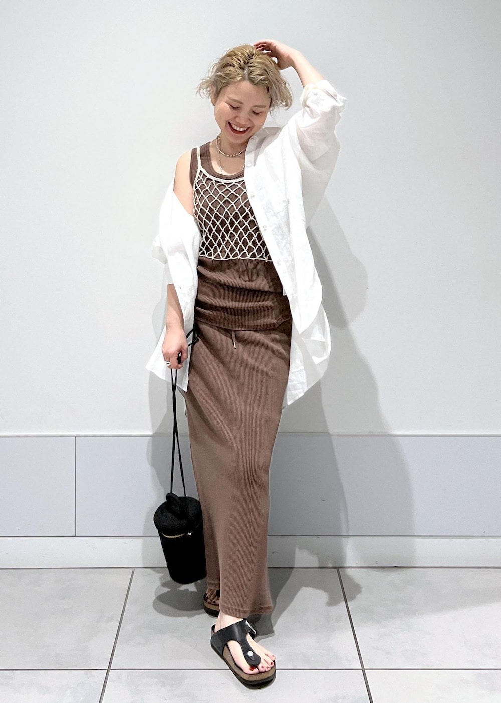 ブラック系のショルダーバッグ、ベージュ系のキャミソール、ブラウン系のタンクトップを着用したレディースの夏コーディネートの2枚目の写真