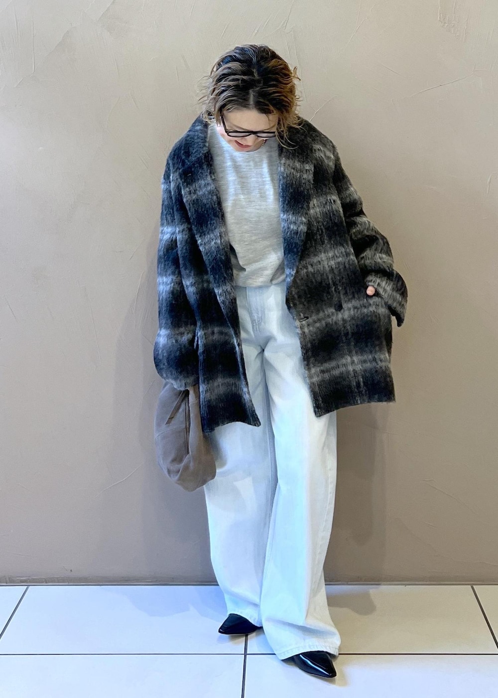 ブルー系のデニムパンツ、グレー系のその他アウター、グレー系のハンドバッグを着用したレディースの秋コーディネートの4枚目の写真