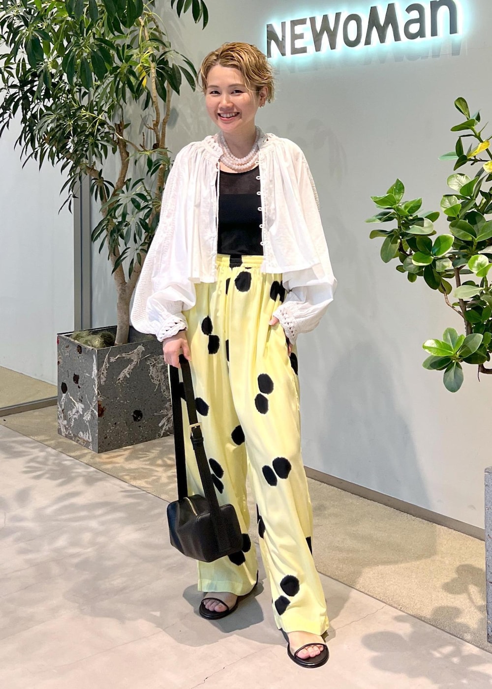 ブラック系のショルダーバッグ、ホワイト系のシャツ/ブラウス、ホワイト系のサンダルを着用したレディースの夏コーディネートの2枚目の写真