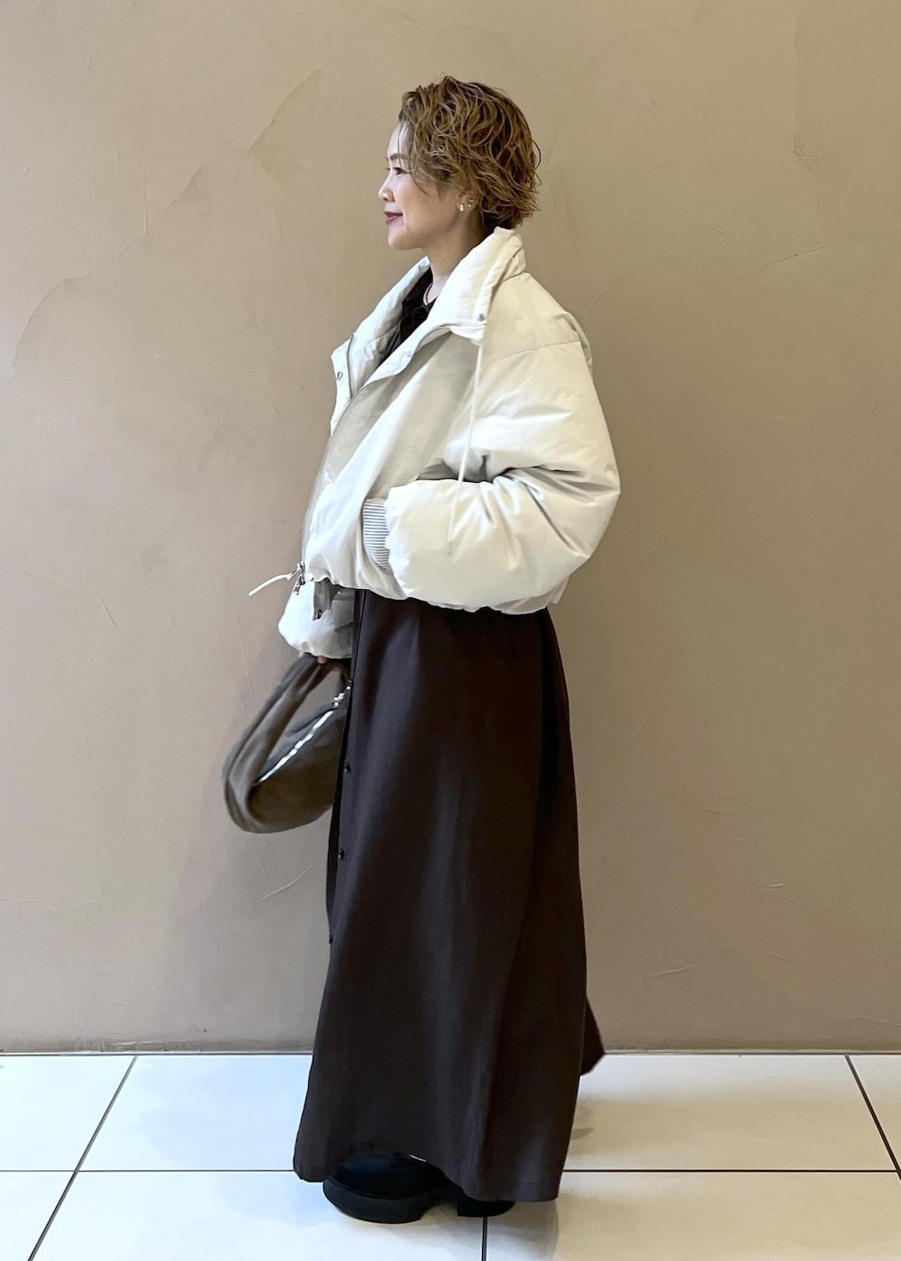 ホワイト系のダウンジャケット/コート、グレー系のハンドバッグ、グレー系のワンピースを着用したレディースの秋コーディネートの6枚目の写真