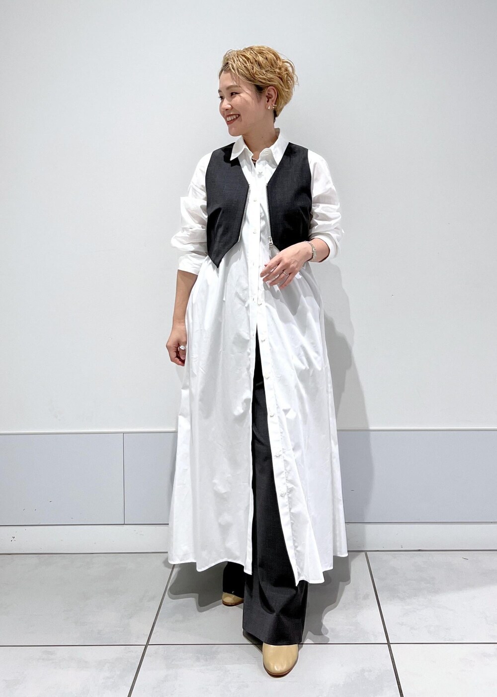 ホワイト系のシャツワンピース、ブラック系のタンクトップ、グレー系のベストを着用したレディースの秋コーディネートの4枚目の写真