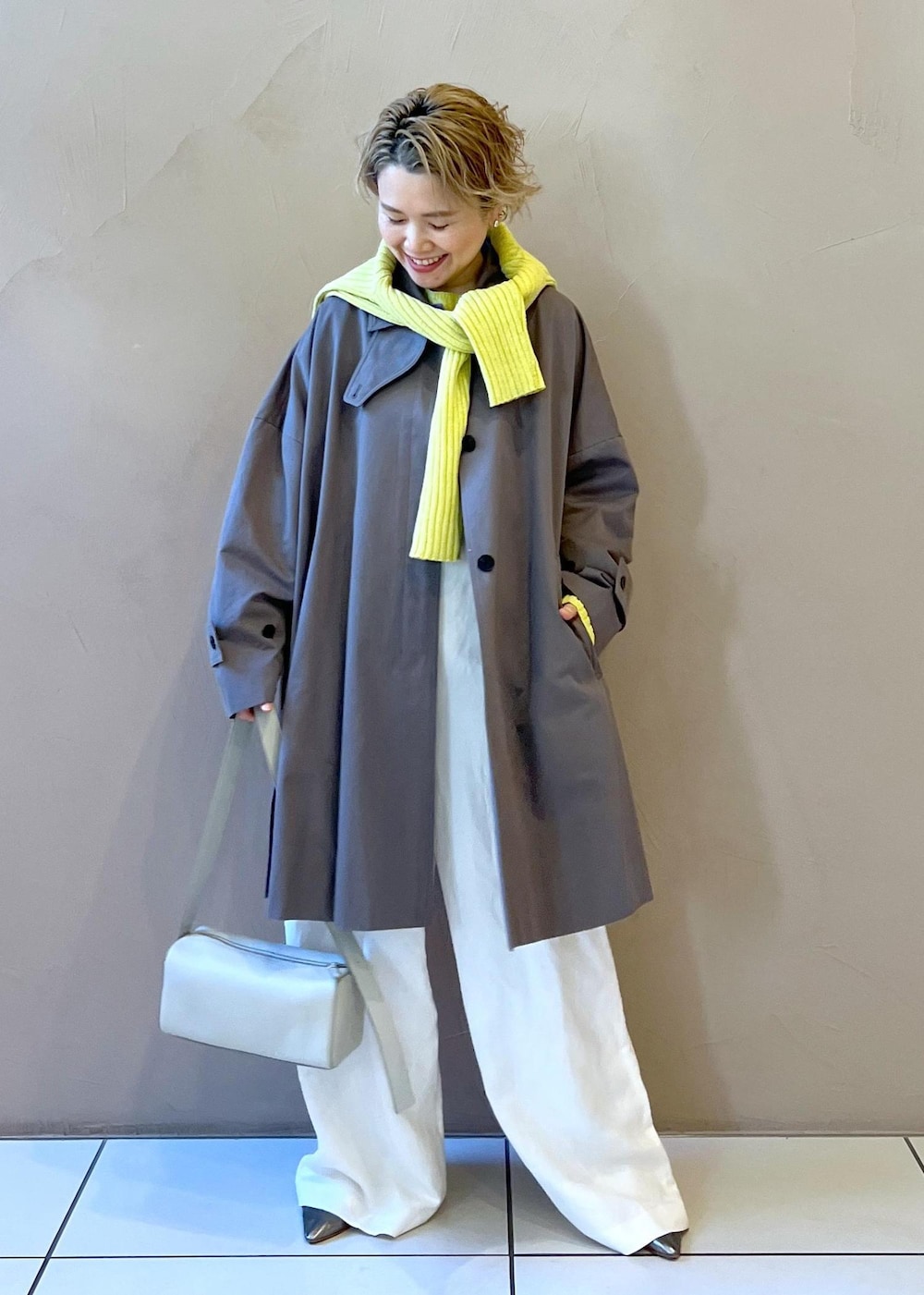 シルバー系のショルダーバッグ、イエロー系のカーディガン/ボレロ、ホワイト系のサロペット/オーバーオールを着用したレディースの冬コーディネートの2枚目の写真