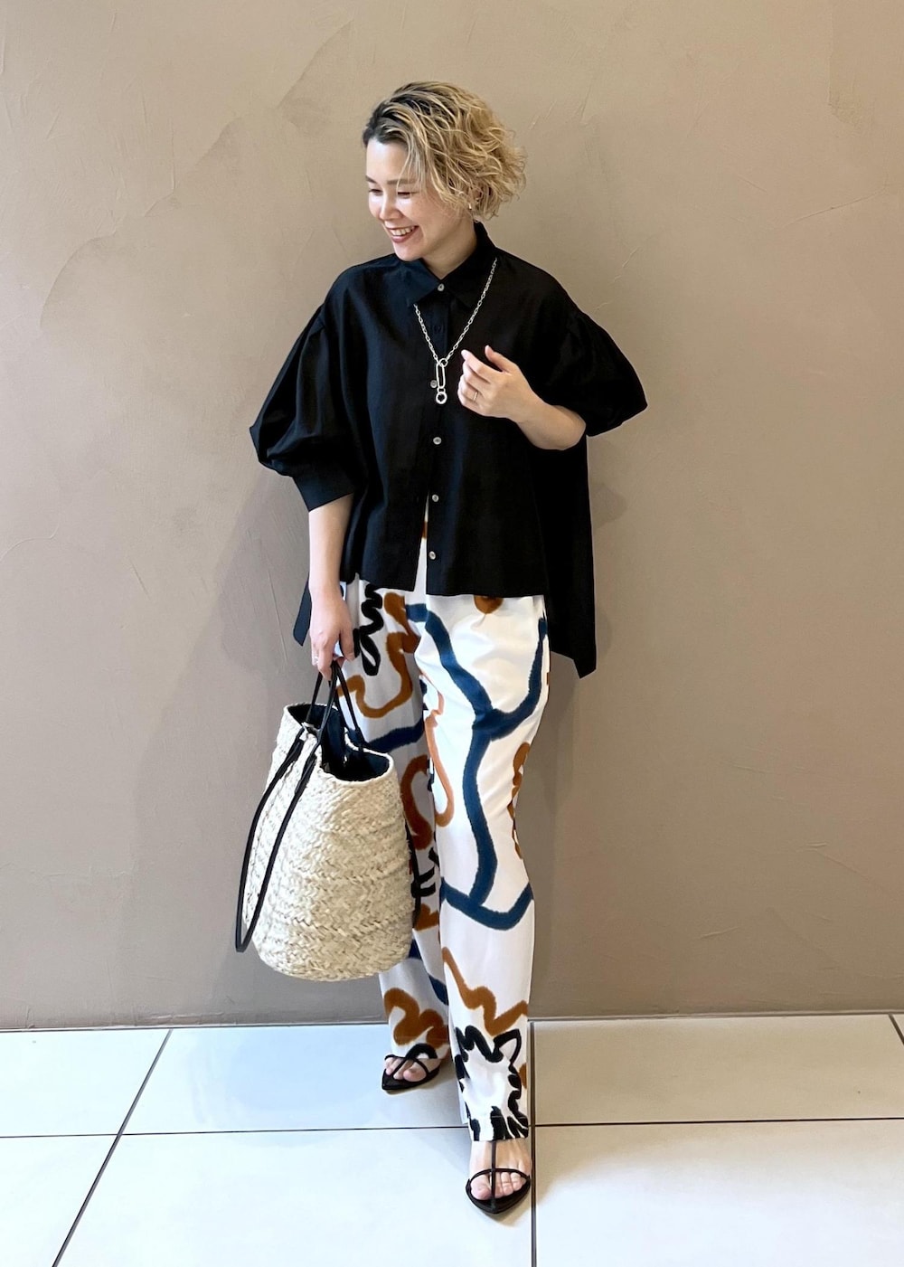 ブラック系のサンダル、ホワイト系のかごバッグ、ブラック系のシャツ/ブラウスを着用したレディースの春コーディネートの3枚目の写真