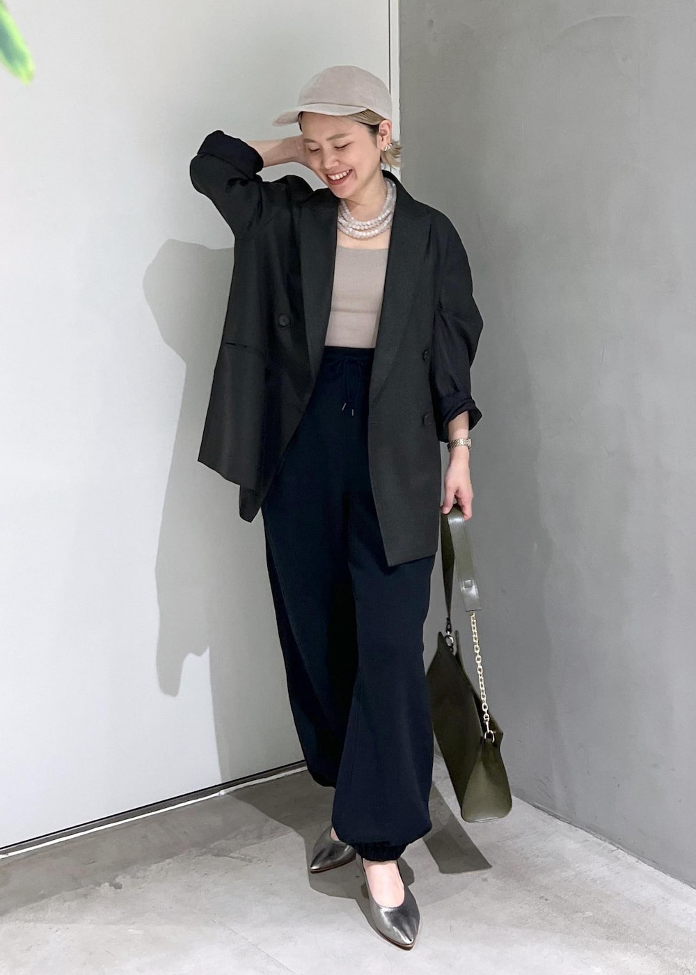 グリーン系のショルダーバッグ、ブラック系のスウェットパンツ、シルバー系のパンプスを着用したレディースの秋コーディネートの4枚目の写真