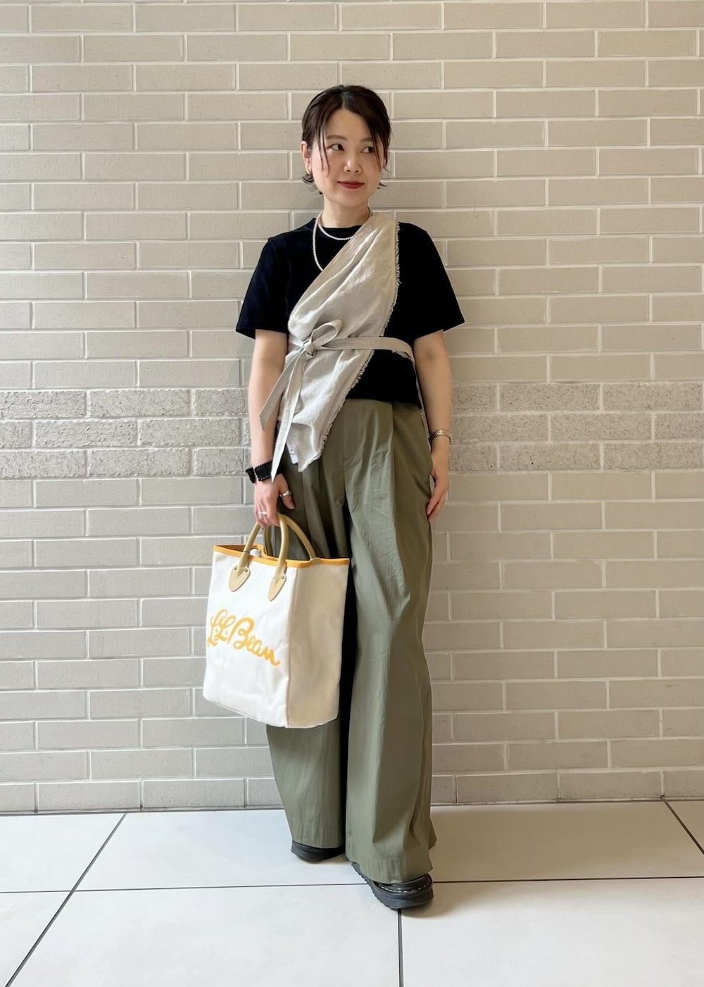 ホワイト系のトートバッグ、ブラック系のTシャツ/カットソー、グリーン系のその他パンツを着用したレディースの春コーディネートの2枚目の写真