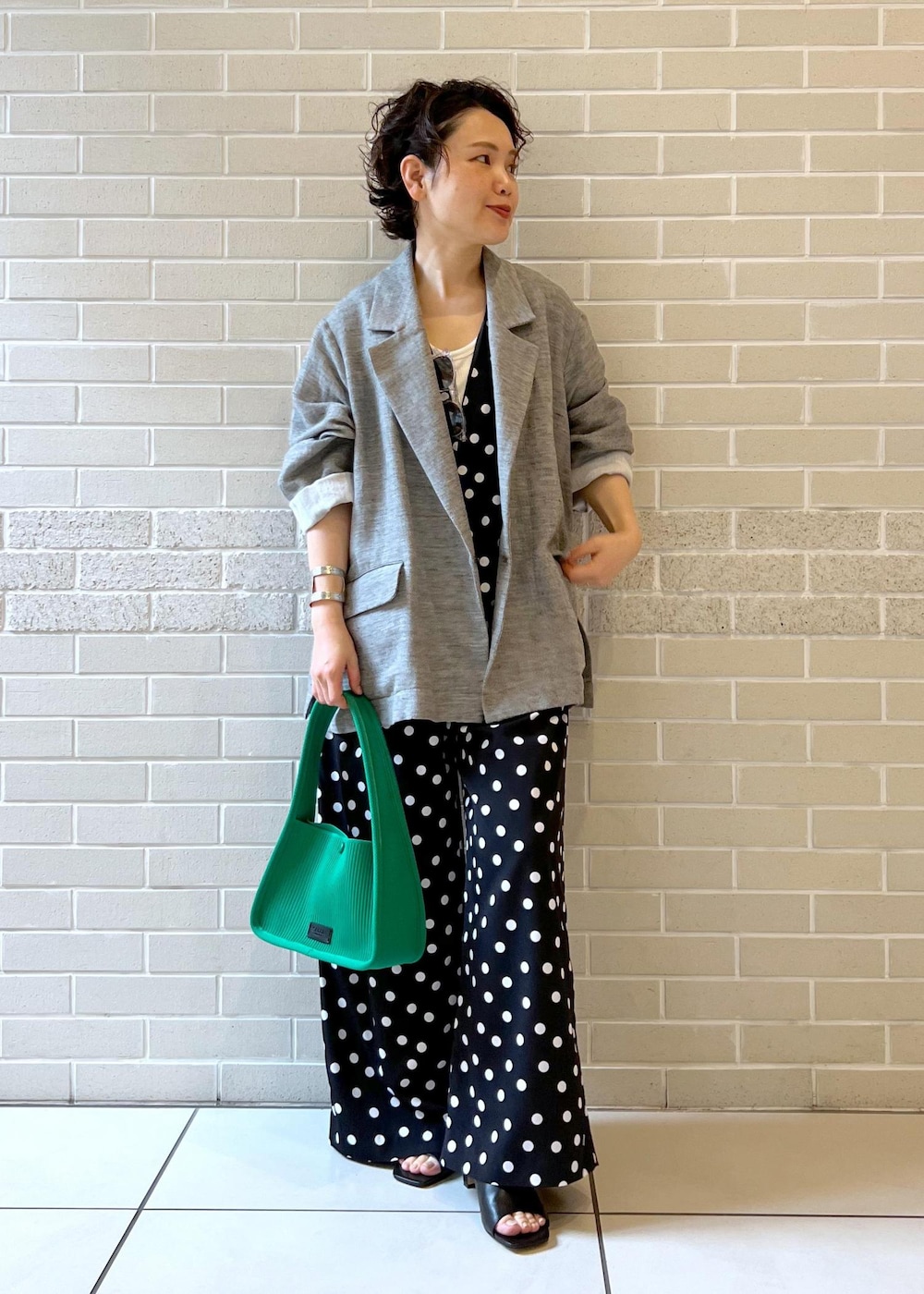 ホワイト系のタンクトップ、グリーン系のハンドバッグ、ブラック系のサンダルを着用したレディースの夏コーディネートの3枚目の写真
