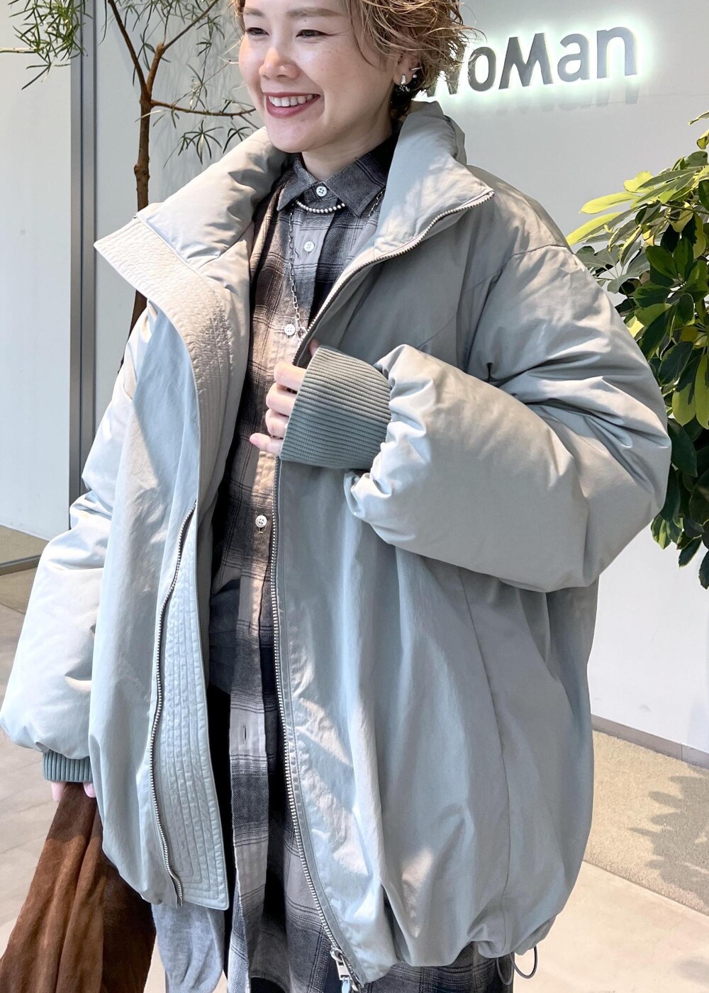 グリーン系のダウンジャケット/コート、ブラウン系のハンドバッグ、ブラック系のブーツを着用したレディースの秋コーディネートの7枚目の写真