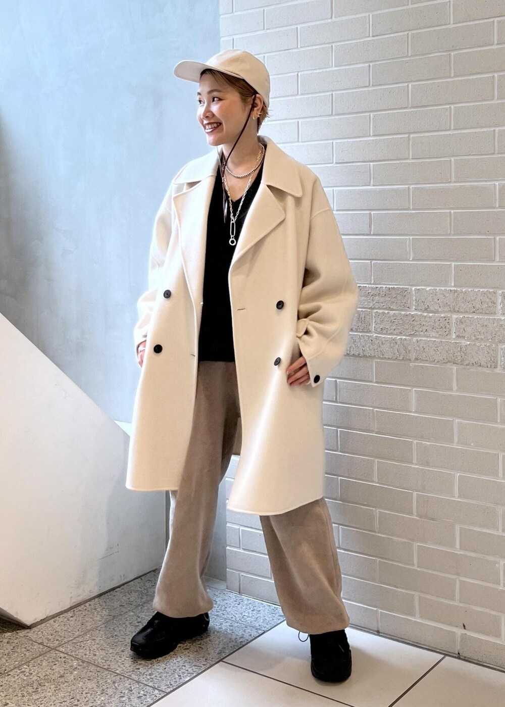 ホワイト系のピーコート、グレー系のカーゴパンツ、ブラウン系のニット/セーターを着用したレディースの秋コーディネートの8枚目の写真