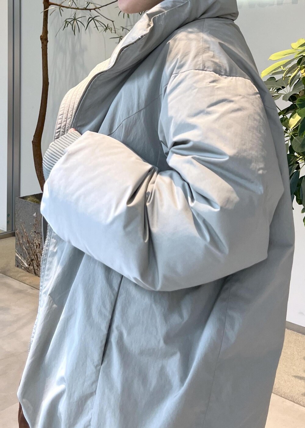 グリーン系のダウンジャケット/コート、ブラウン系のハンドバッグ、ブラック系のブーツを着用したレディースの秋コーディネートの8枚目の写真