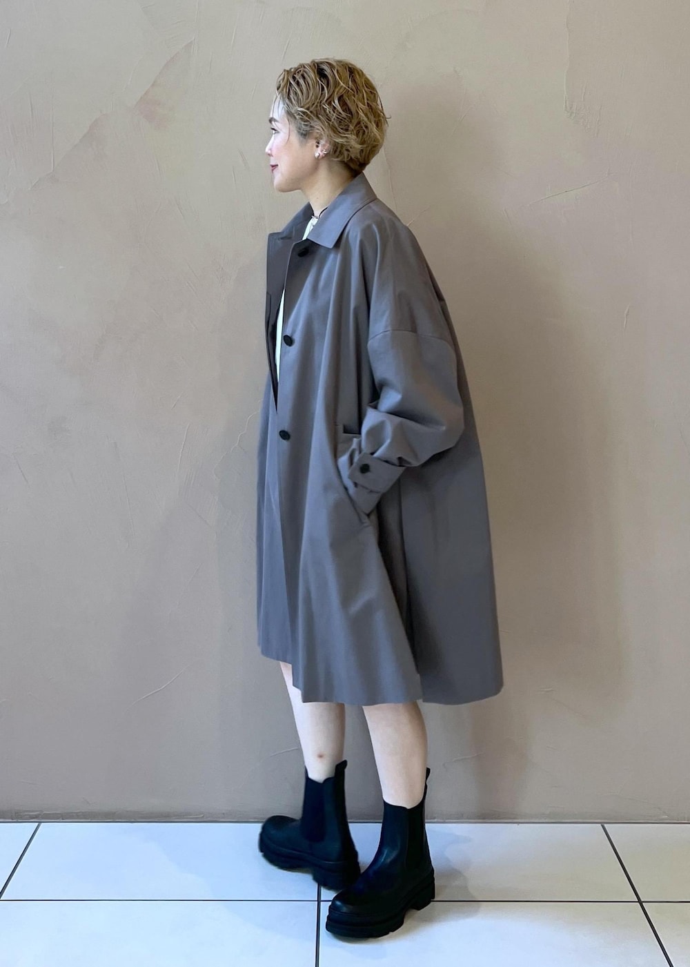 ブラック系のブーツ、ホワイト系のニット/セーター、グレー系のステンカラーコートを着用したレディースの冬コーディネートの5枚目の写真