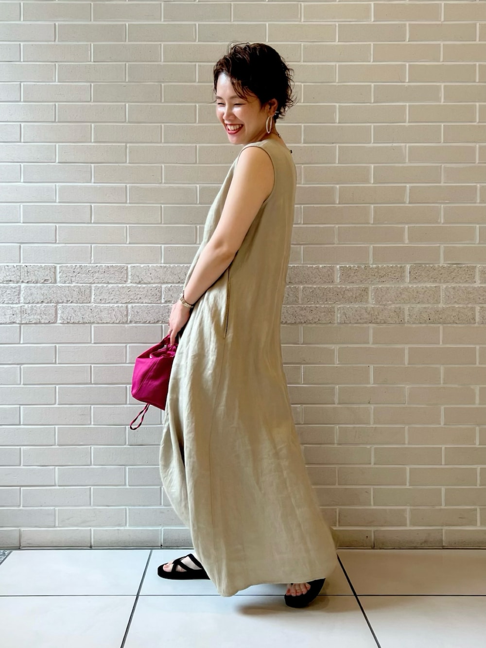 グリーン系のワンピース、ピンク系のハンドバッグ、ブラック系のサンダルを着用したレディースの夏コーディネートの2枚目の写真