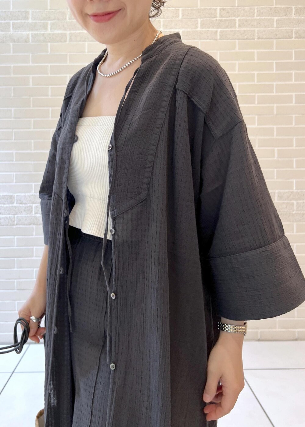 ホワイト系のチューブトップ、ベージュ系のサンダル、ブラック系のシャツ/ブラウスを着用したレディースの夏コーディネートの7枚目の写真