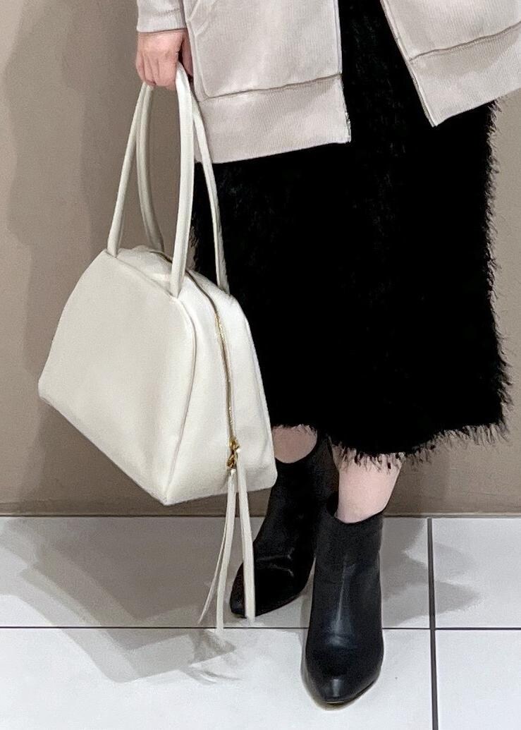 ベージュ系のパーカー、ホワイト系のボストンバッグ、ブラック系のブーツを着用したレディースの秋コーディネートの8枚目の写真