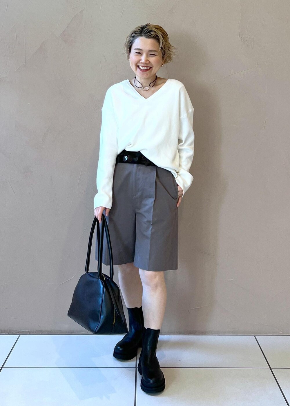 ブラック系のブーツ、ホワイト系のニット/セーター、グレー系のステンカラーコートを着用したレディースの冬コーディネートの9枚目の写真