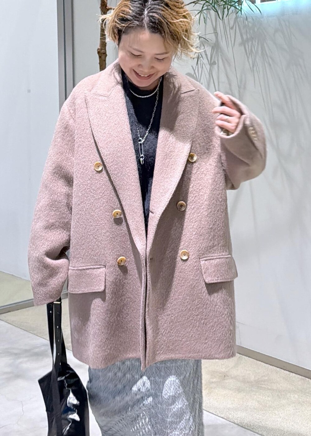 ブラック系のショルダーバッグ、グリーン系のスカート、ブラウン系のチェスターコートを着用したレディースの秋コーディネートの6枚目の写真