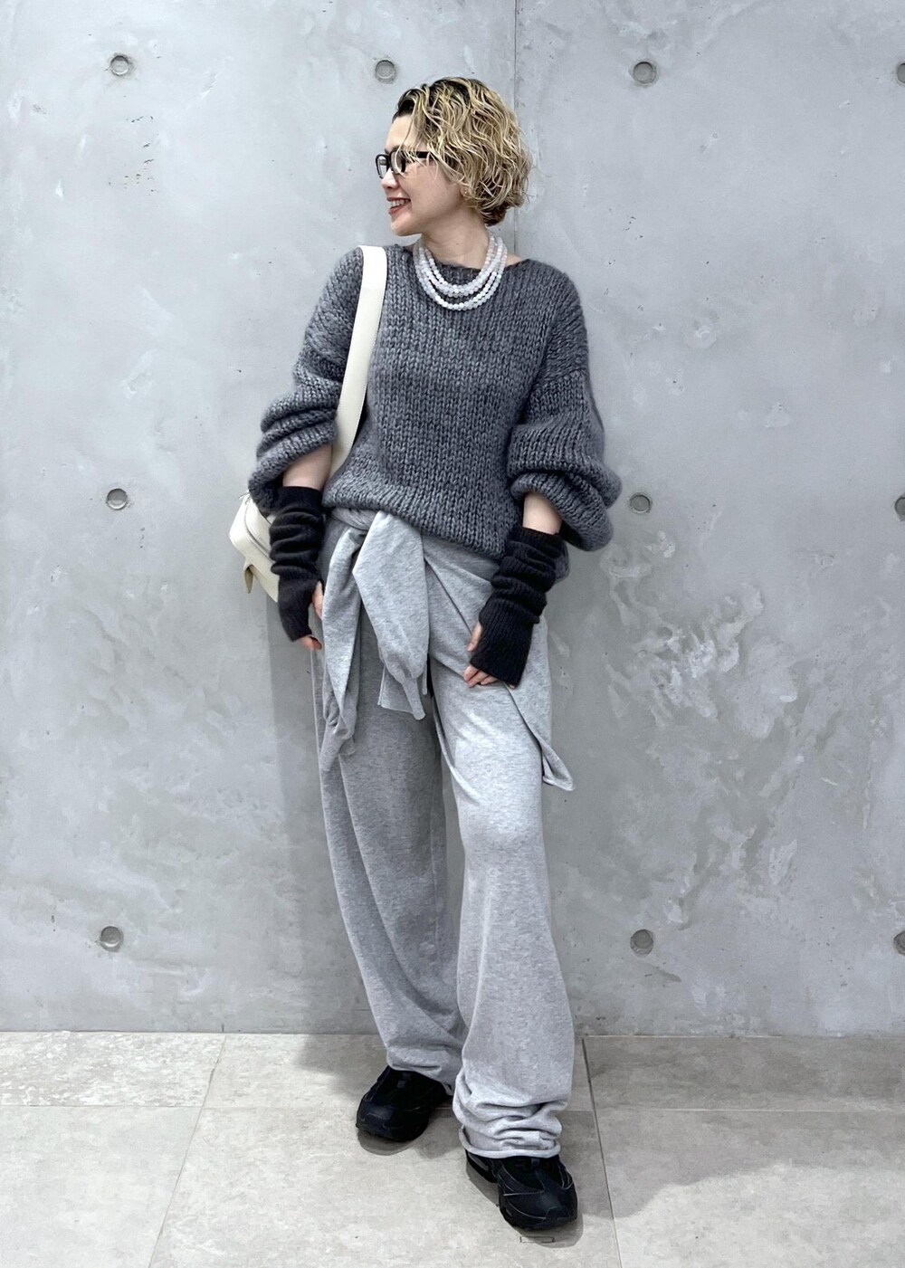 グレー系のニット/セーター、ホワイト系のボディバッグ/ウエストポーチ、グレー系の手袋を着用したレディースの秋コーディネートの2枚目の写真