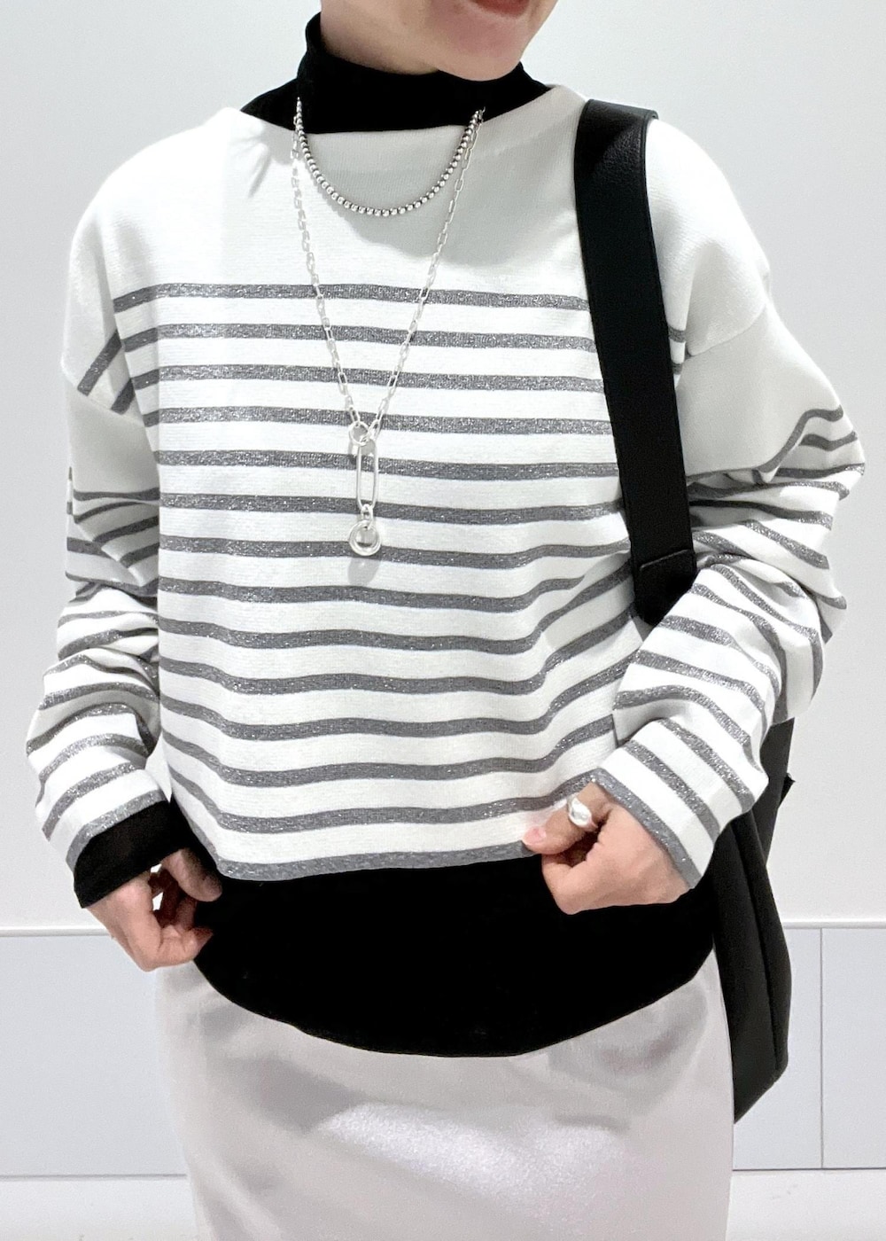 ブラック系のブーツ、ブラック系のTシャツ/カットソー、シルバー系のスカートを着用したレディースの冬コーディネートの6枚目の写真