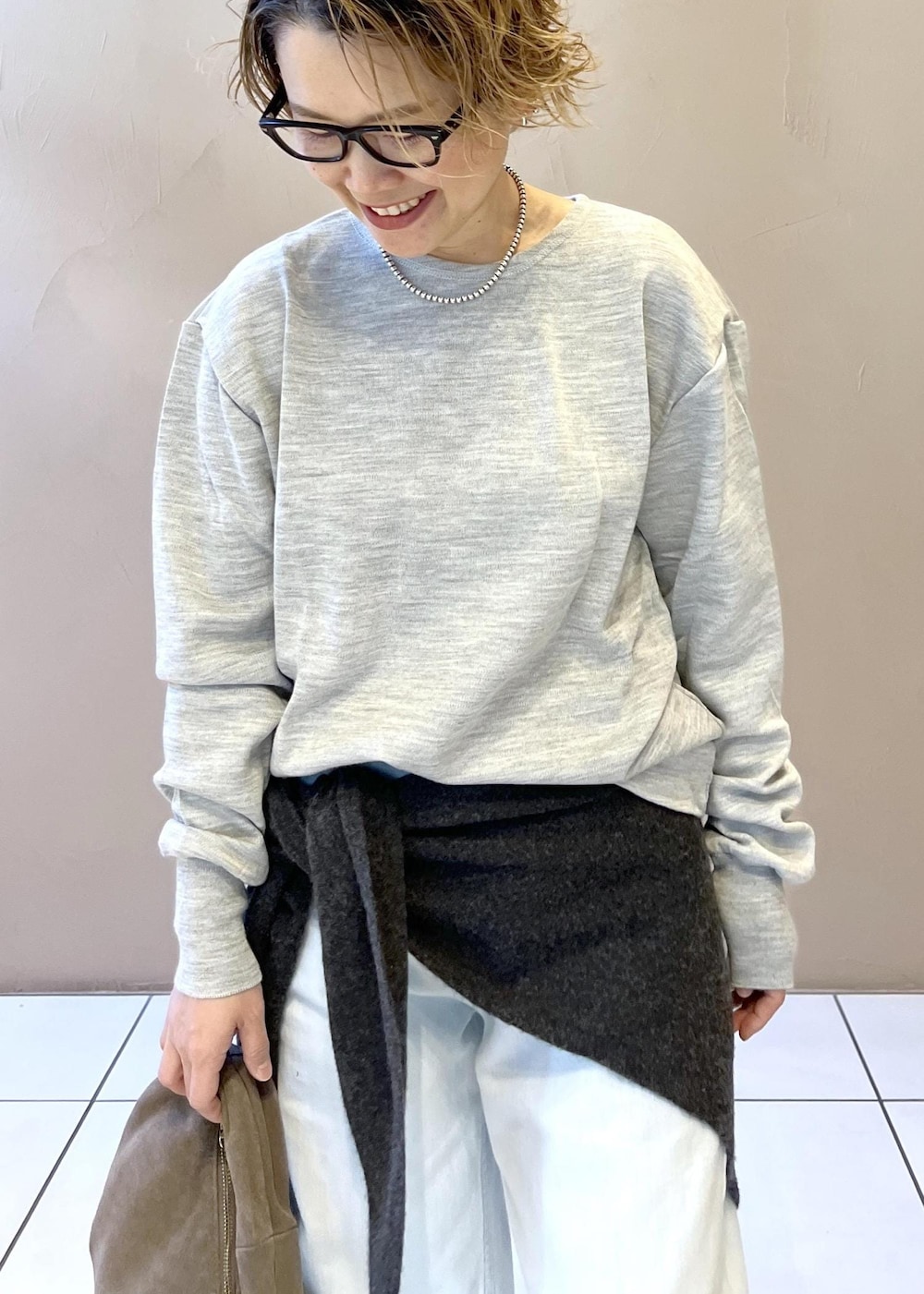 ブルー系のデニムパンツ、グレー系のハンドバッグ、ブラック系のパンプスを着用したレディースの秋コーディネートの6枚目の写真