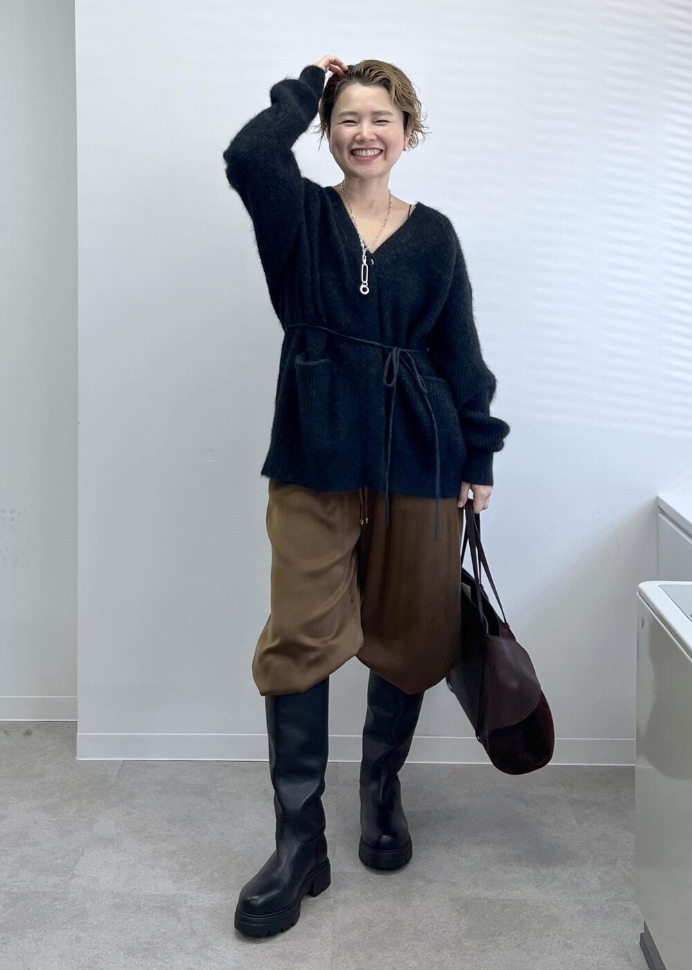 ブラック系のブーツ、ブラウン系のその他パンツ、グレー系のカーディガン/ボレロを着用したレディースの秋コーディネートの3枚目の写真