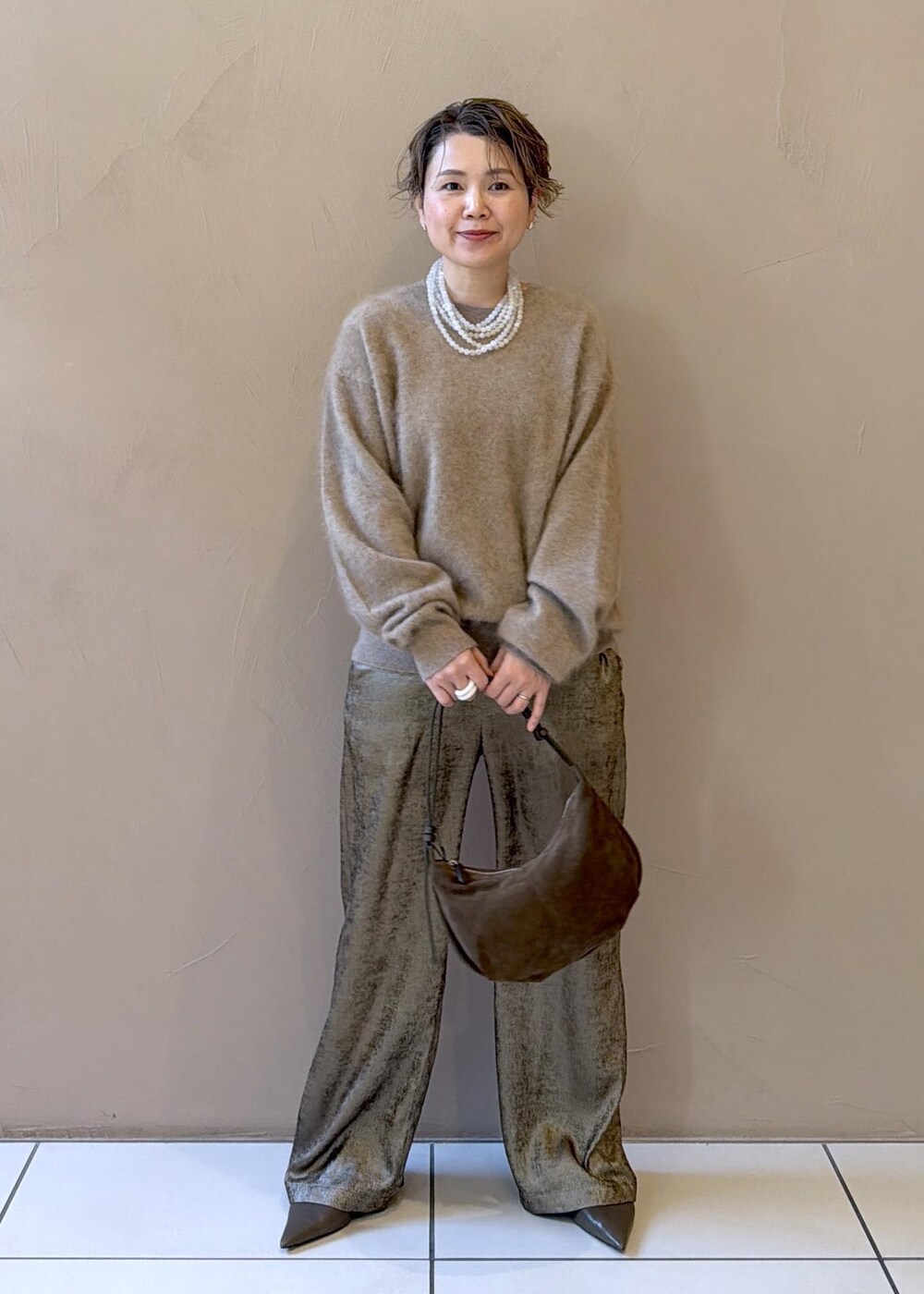 ゴールド系のその他パンツ、ベージュ系のニット/セーター、グリーン系のパンプスを着用したレディースの冬コーディネートの5枚目の写真